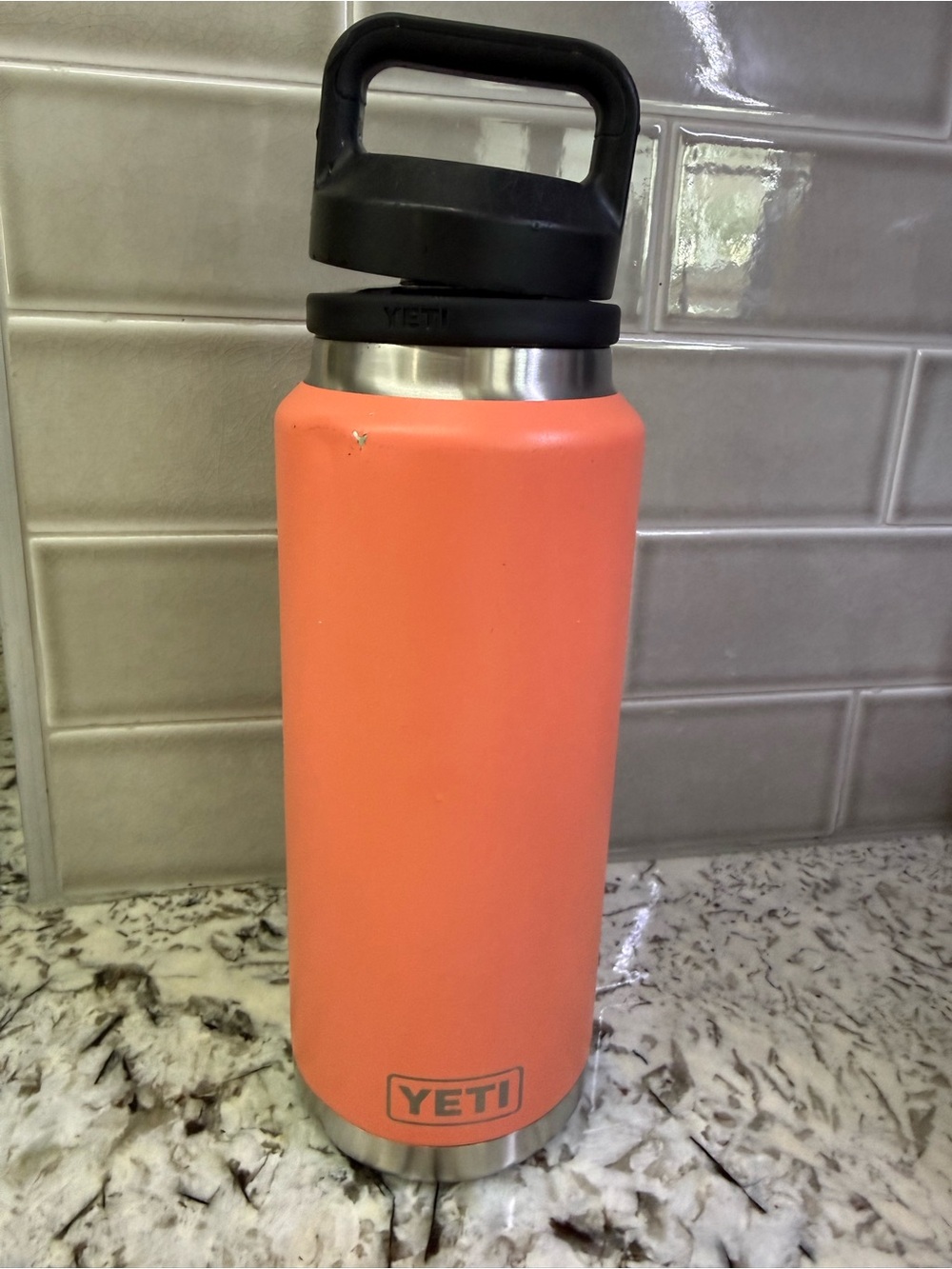 Yeti Coral Orange Rambler Bottle with Black Handle Lid.